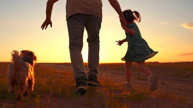 A man and a girl run together into the sunset, joined by a dog. The scene captures a joyful moment of family, with the girl and dog excitedly playing in the evening light.