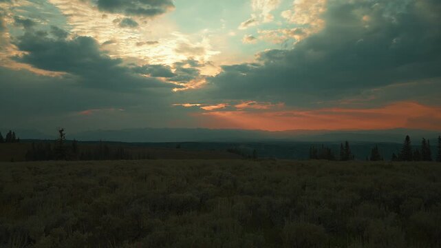 Teal and orange sunset clouds with light rays over high meadow, time lapse, Utah