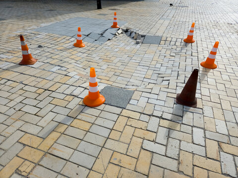 Damaged sidewalk paving tiles traffic cones warning repair city street road works hazard danger pedestrian infrastructure urban