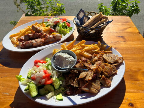 Greek tavern. Plate with gyros, pork kebab with vegetables, tomato and cucumber. Tzatziki sauce. Portion of pita bread with souvlaki