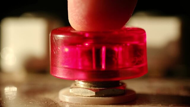 Close up finger pushing large red illuminated button on industrial control panel symbolizing crucial decision, alarm activation, emergency stop procedure. Person pressing glowing red emergency button