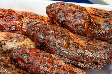 Whole Marinated Fish with Reddish Brown Seasoning Displayed on Counter at Traditional Seafood Market © Zaiteva Irina