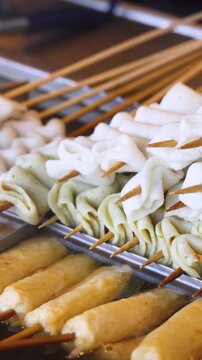 Eomuk odeng, assortment of Korean fish cake skewers on display at a street food stall in Jung-gu, Busan, Yeongnam, South Korea, white, green and fried varieties on bamboo sticks at a night market