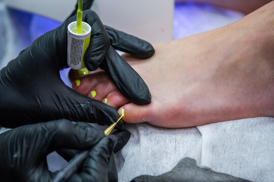 In a beauty salon, the treatment focuses on a pedicure, toenail polish, nail polish application, nail polish, a nail technician, and the toenail