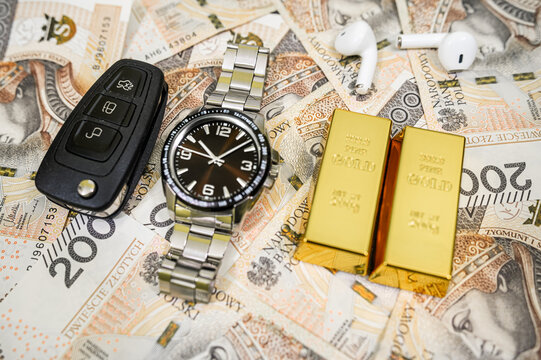 Top View of Men Wristwatch Gold Bars Car Key and Wireless Earbuds on 200 PLN Money Bills Frame