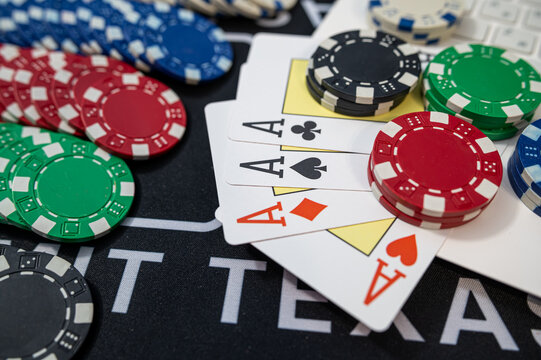 Four Aces Playing Cards Combination with Stacks of Casino Chips on Black Felt Table Surface