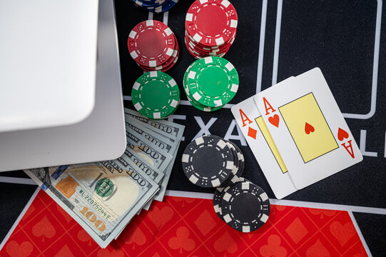 White Laptop with US Dollar Bills Pocket Aces Cards and Casino Chips for Online Gambling Concept