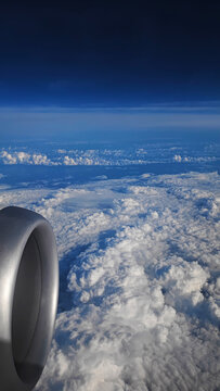 Airplane engine and layered cloudscape from window with blue sky and horizon