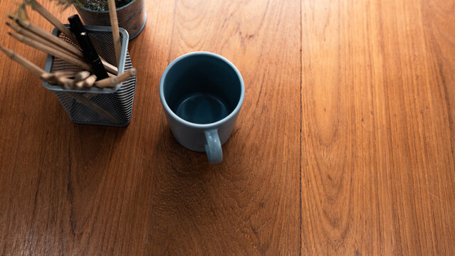 top view of a coffee mug with wooden pencils and pens on a wood grain desk.