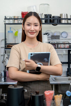 Smiling caf&eacute; owner holding a tablet behind a coffee shop counter.
