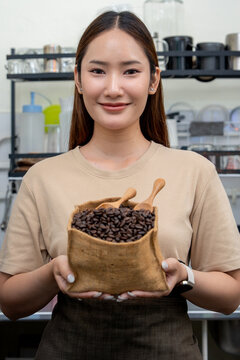 A small business owner presents a rustic bag of whole roasted coffee beans at her coffee shop counter.