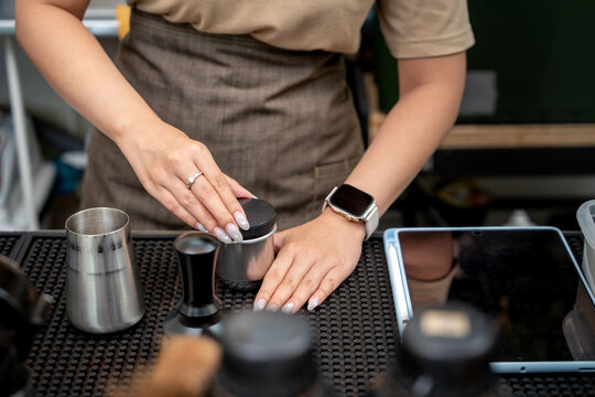 Barista using a macaron distributor to level coffee grounds at a caf&eacute;.