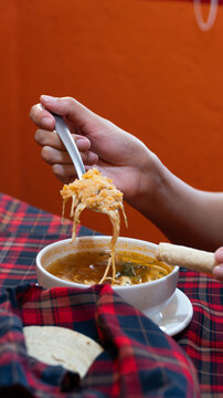 Mano levantando una cucharada de sopa mexicana