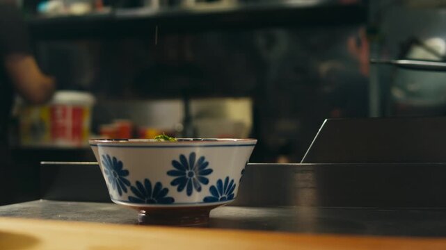 Ramen bowl with noodles served in Japanese restaurant, chef putting fresh noodles into hot soup bowl, traditional asian ramen dish with broth and toppings