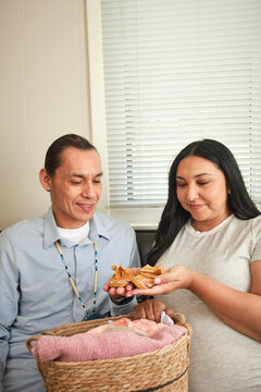 Native American couple prepares for baby in sun room by exploring items in basket