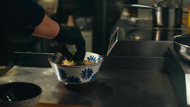 Ramen bowl with noodles served in Japanese restaurant, chef putting fresh noodles into hot soup bowl, traditional asian ramen dish with broth and toppings