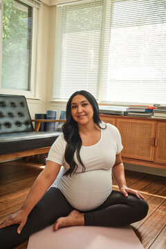 Native American expectant mother practices yoga in sun room during pregnancy