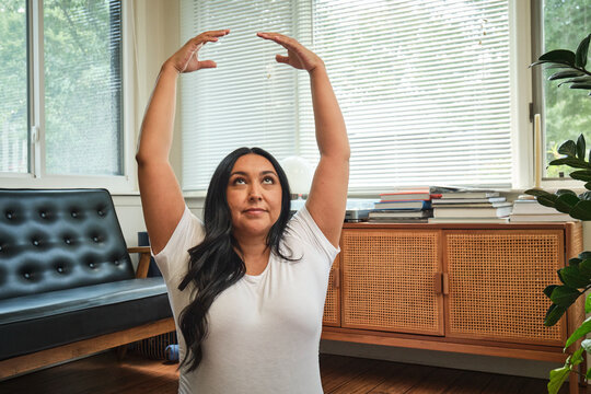 Native American expectant mother practices yoga in sun room on mat