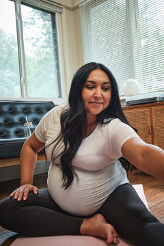Expecting mother stretches in sun room during yoga practice