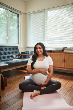 Native American expectant mother practices yoga in sun room during morning hours