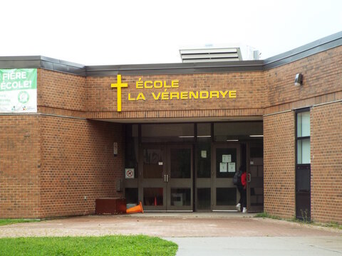 Gloucester, Ontario, Canada &ndash; August 3, 2026: "L'entr&eacute;e en briques de l'&Eacute;cole La V&eacute;rendrye" comporte une croix jaune, un lettrage dor&eacute; et des portes vitr&eacute;es at 614 Eastvale park.
