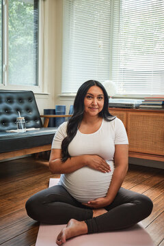 Pregnant Native American mother practices yoga in sun room