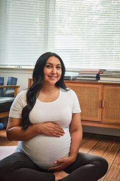 Native American expectant mother stretches in sun room during yoga practice