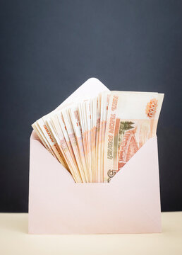  holding an envelope containing 5,000-ruble banknotes; a display of Russian currency, possibly representing profit.