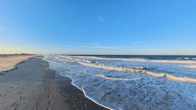  long sandy beach stretches beyond foamy breakers in this 4K coastal video.