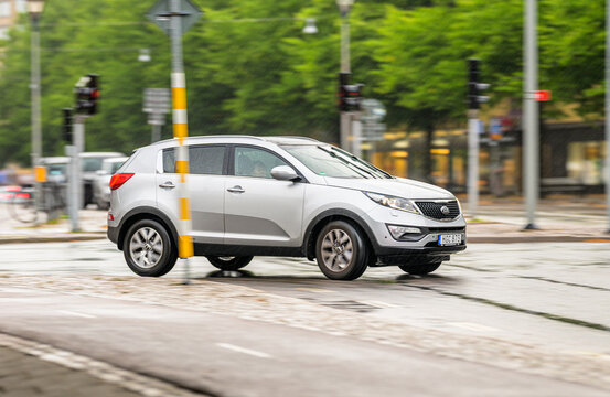Gothenburg, Sweden - July 28 2026: Silver Kia Sportage SUV turning across wet Swedish intersection.
