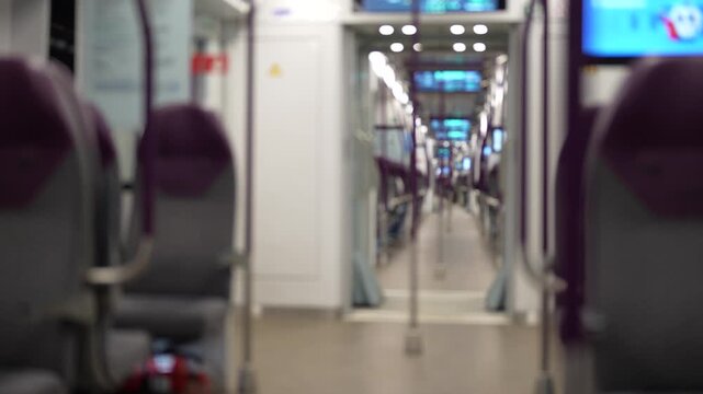 Modern passenger train carriage viewed along the central aisle with rows of seats, illustrating public transportation, railway travel, daily commuting and contemporary passenger mobility