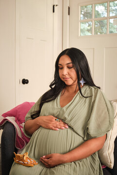 Native American pregnant woman sitting in a cozy indoor setting