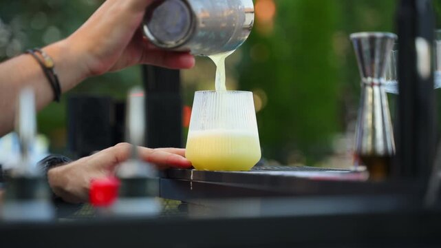 Bartender Pouring a Yellow Cocktail into a Glass