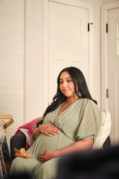 Native American pregnant woman sitting on a chair in a simple home setting