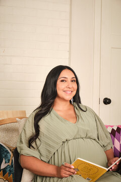 Native American pregnant woman reading a book in a cozy indoor setting