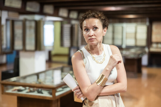 Interested woman looking at collection of medieval sculptures and objects in museum