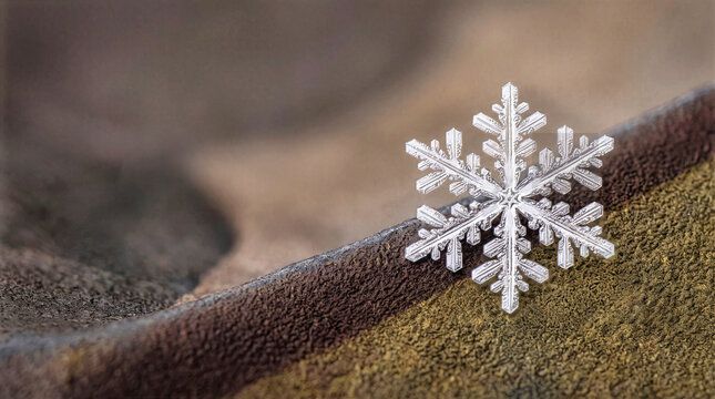 Macro photograph of a single hexagonal snow crystal ice flake resting on a textured brown and green fabric surface. Detailed close-up of winter snowflake highlighting intricate ice geometry