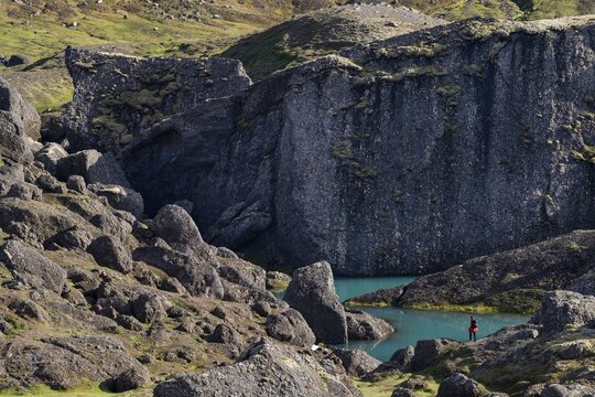Woman standing in front of turquoise water pool, St&oacute;rur&eth; landslide in Dyrfj&ouml;ll, Iceland