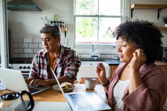 Woman inserts earbud as couple works at kitchen table