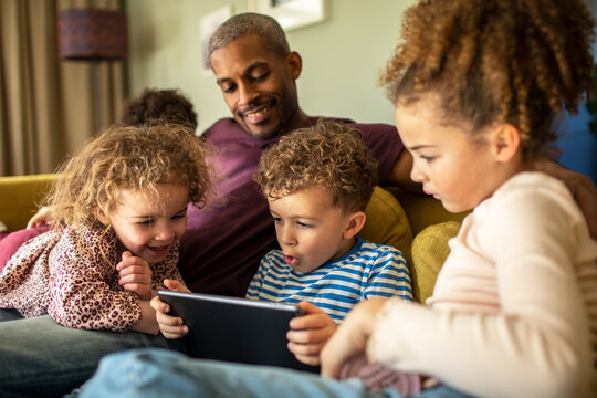 Father and children watching a tablet on the sofa
