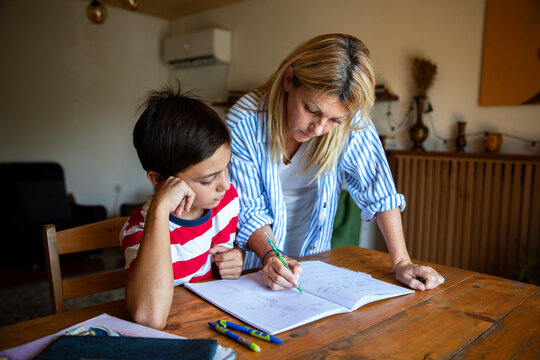 Woman helping boy with math homework at home