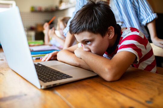 Tired boy slumped at laptop during online homework