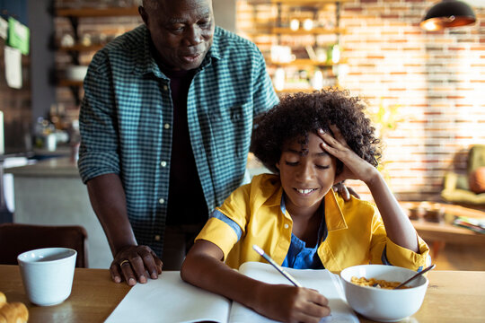 Boy doing homework with adult help at kitchen table