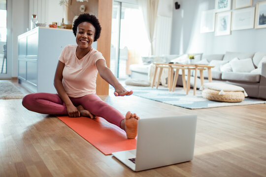 Smiling woman stretching during online yoga session at home