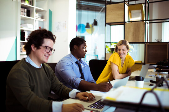 Coworkers collaborating as teammate takes notes in open office