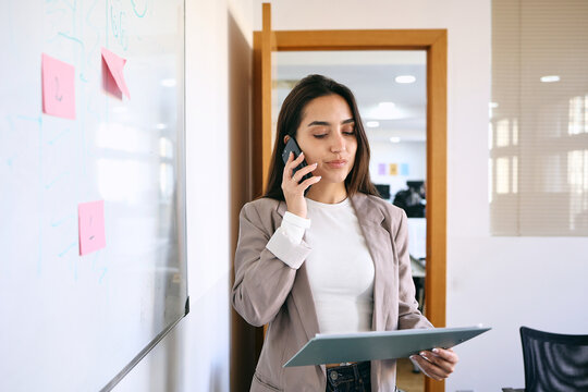 young latin businesswoman talking by phone in a call at office in Latin America, hispanic female working at workplace