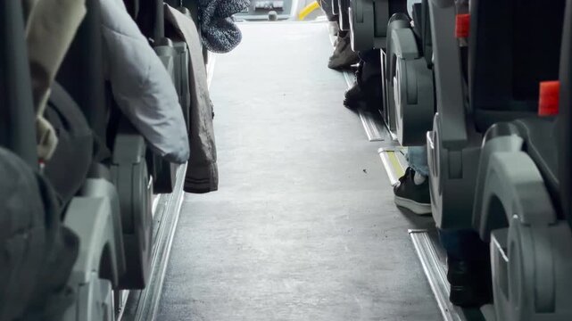 Passengers sit quietly in rows along the aisle inside a bus. The neat interior creates a calm and relaxed feeling. Bright daylight fills the peaceful ride.
