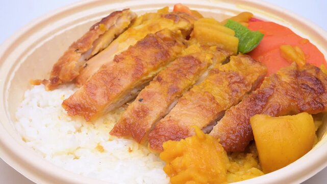 Sliced grilled chicken curry rice served in disposable bowl