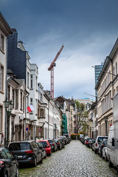 Citadellstrasse in central Dusseldorf, Germany, with cobblestones, multistorey buildings and cars parked along both sides. Traditional facades and street lamps characterise this historic streetscape.