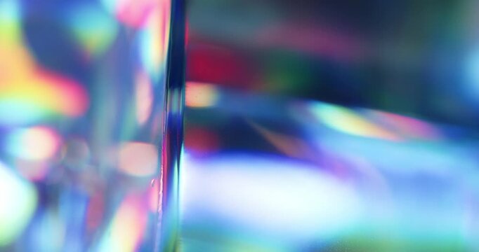 Light reflecting glass in brilliant saturated colors. Radiant lighting through a prism cube creating a visual of a colorful rainbow effect of light refraction. Spinning geometric abstract background.